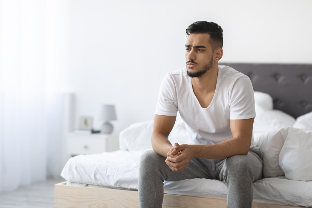 man sitting on edge of bed.